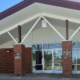 Juvenile solitary confinement: Lathe one-story red brick building entrance with pillars, white trim and triple glass doors.