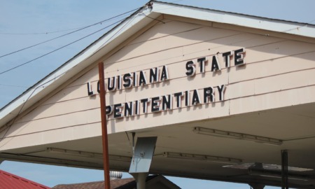 Juveniles in Angola Prison: Close-up of peaked, beige-siding roof over a drive-through entrance, with black lettering, "Louisiana State Penitentiary"