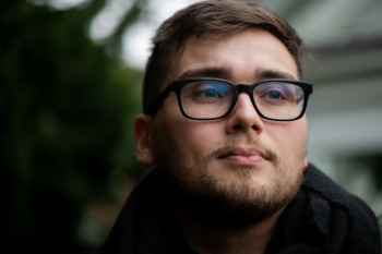 Homeless lifeline Washington state: Headshot of Daniel Lugo. man with brown hair and vlack-framed glasses in dark winter jacket