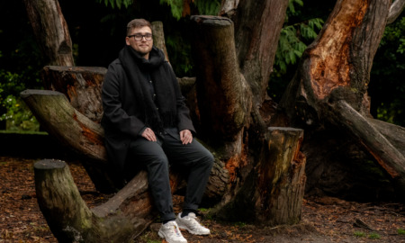 Homeless lifeline Washington state: Man with brown hair in dark pants and winter jacket leans against tree on park pathway