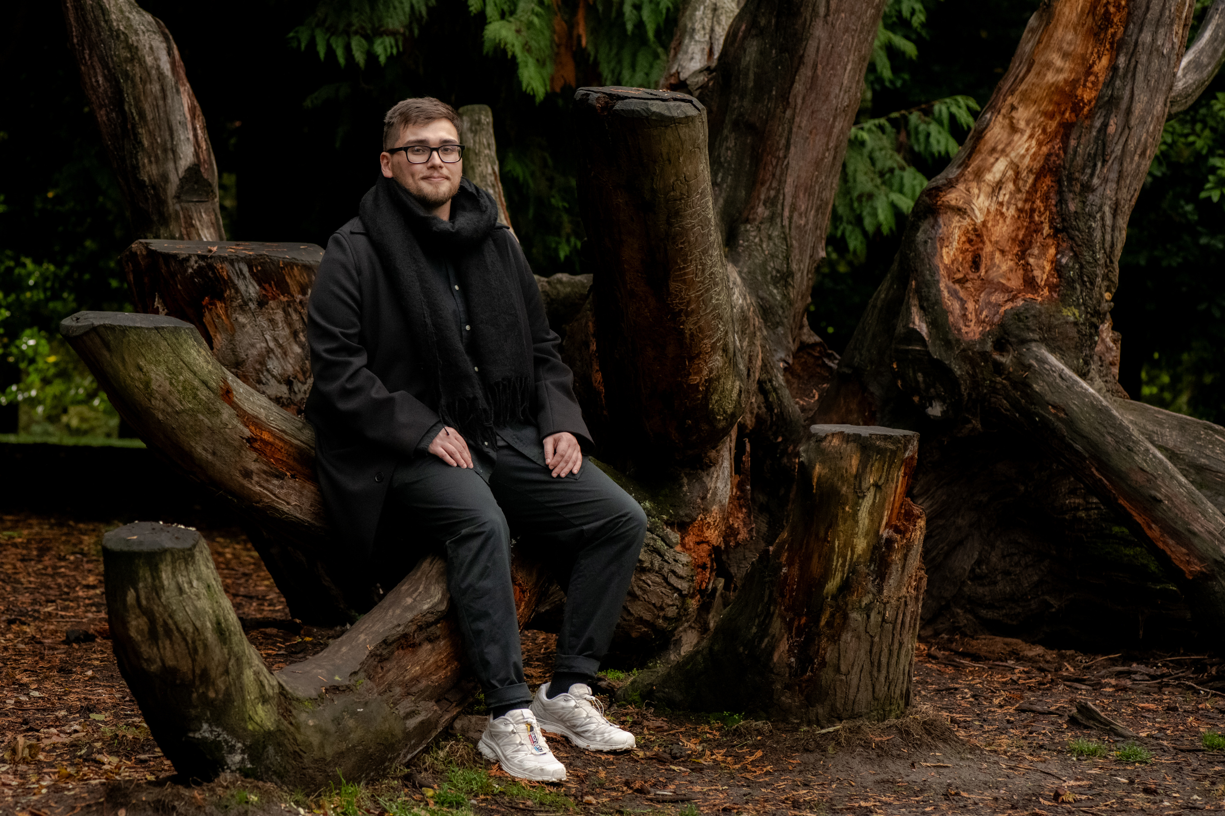 Homeless lifeline Washington state: Man with brown hair in dark pants and winter jacket leans against tree on park pathway