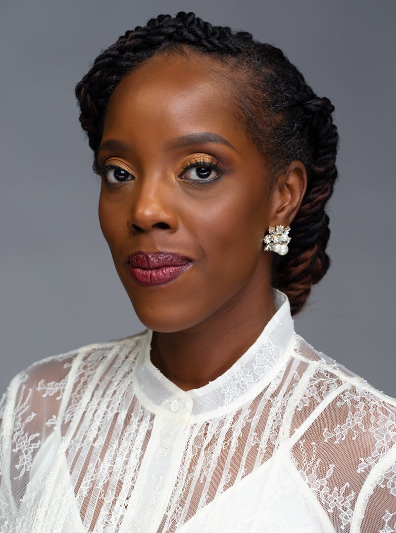 Guaranteed income: Headshot of Black woman with back haor pulled back in white , lacy top looks solemnly into camera.