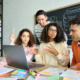 iCivics curridylum: Four older students sit around laptop at table covered in multi-colored note papers in active discussion