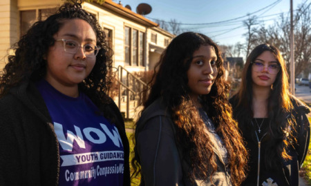 Ethnic sipport middle school girls: A young woman and two young teen girls stand next to each other outside in front of a multistory building on a sunny day