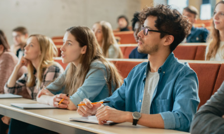 Autistic students college success tips: Several college students sit at rows of desks on risers