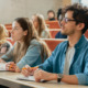 Autistic students college success tips: Several college students sit at rows of desks on risers