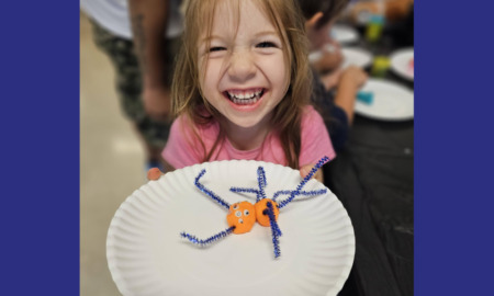 AI afterschool: Smiling elementary school redheaded girl in punk shirt shows off project displayed on white paper plate