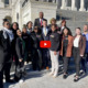 Youth Adult Tax Credit: Group of several people stand together in two rows on steps of large white cement building with white pillars