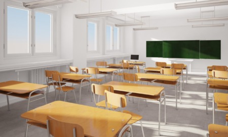 Louisiana school funding: Empty white classroom with rows of light wood desks and chairs facing a blackboard.