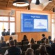 College Male Enrollment: Two young men in navy suits stand at front of seated group next to a presentation slide om bright blue with white text