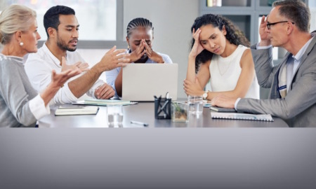 School boards: Group of multi-ethnic adults in business clothes sitting around table talking with expressions of disagreement