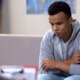 Community-youth-violence-prevention: Black teen sullenly sits on couch across from counselor