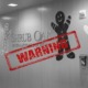 Shrub Oak School investigation: photo of wall with school name surrounded by 3 very large cutouts of gingerbread men colored in child-like style all with a large red "warning" sign with thick border around it