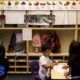 Undocumented students: Three young, dark-haired students sit at low tables in elementary classroom in front of wooden cubbies and colorful alphabet wall decorations