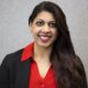 Newsmaker Maheen Kaleem headshot; smiling Pakistani-American woman with suit jacket and red shirt