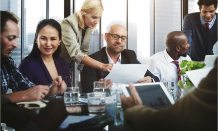 Post-Pandemic Nonprofit: Group of 6 people in active discussion sit & stand around conference table