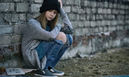 sex trafficking: Homeless teenage girl sitting near brick wall outdoors