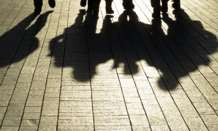 No Place for Kids; Silhouette of feet and legs abd their full body shadows of four people in cobblestone walkway