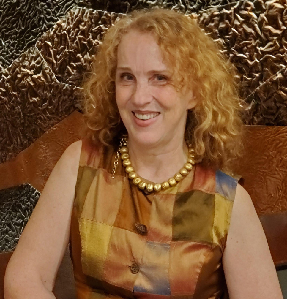 Book banning: Headshot of woman with curly, blonde hair wearing earth-toned color block top seated on a couch.