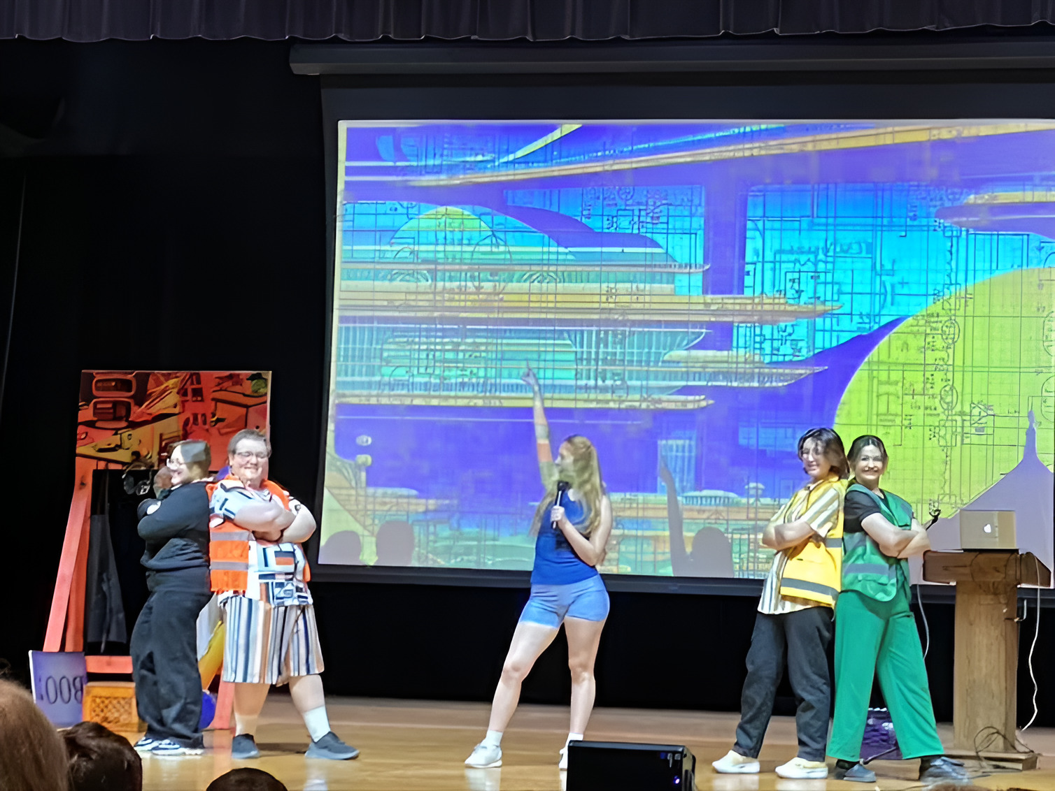 Arts in STEM: Several teens in costumes stand on theater stage with five pieces of art all larger than a person