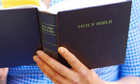 Bible teaching Oklahoma public schools: Close up of a man or woman reading a navy blue Christian Bible.