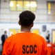 prisoners want more education in prison: young black prisoner in orange garb looking at something