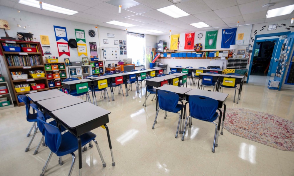 Absenteeism: Wide angle view of empty elementary school classroom with interactive whiteboard no people and lights turned on.