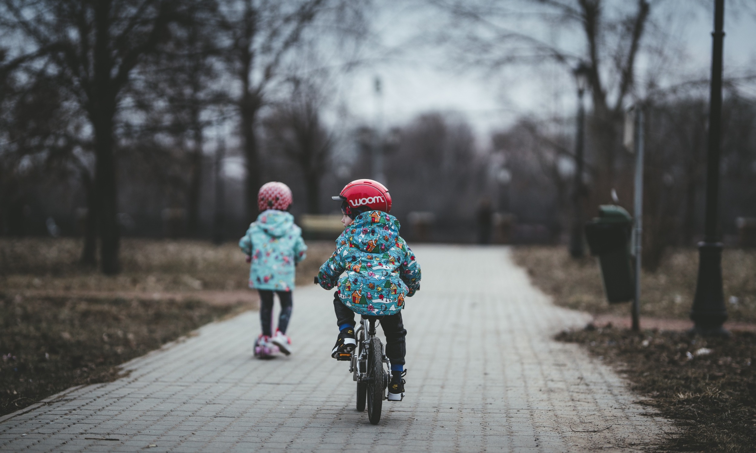 Poor rural kids earn more than poor urban; two-parent household may be the reason: two children riding a bike and scooter down pathway in cold weather