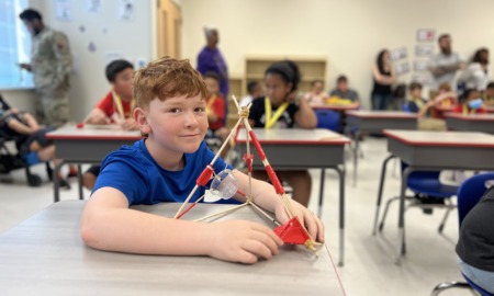 Post-COVID summer programs: young male student at desk shows his pyramid-shaped project