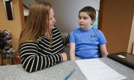 disabled youth informal suspension: mother and child with hearing aid sitting at table