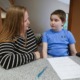 disabled youth informal suspension: mother and child with hearing aid sitting at table