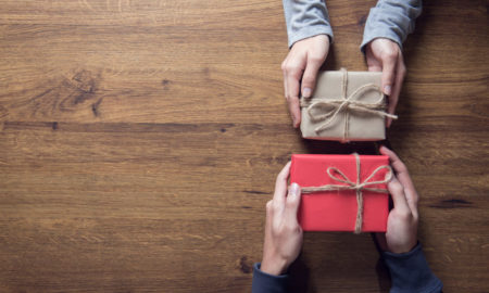 Improving year-end giving tips: hands holding gifts to give on wooden table