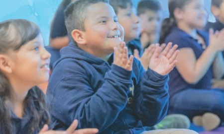 developing social and emotional competencies in OST programs: happy youths sitting on ground clapping