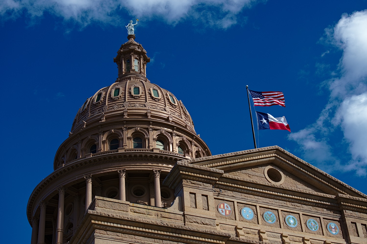 State laws threaten academic freedom in higher education: view looking up at Texas state capitol building with U.S. flag and Texas flag flying