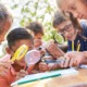 Condition of education report 2024: group of young students outdoors looking at something with magnifying glasses