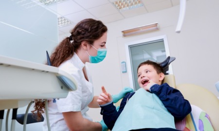 tips for finding dental care for disabled youth: happy child looks up at female dentist in dentist's chair