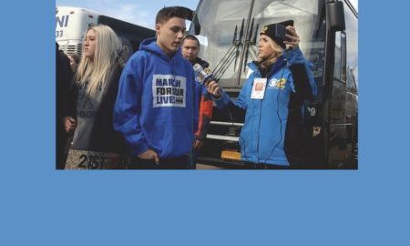 Student Walkout teen male portester being interviewed by female news reporter standing in front of bus he will ride to new York walkout.