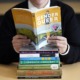 Walking on eggshells; teacher's responses to classroom limitations: person holding a book titled "Gender Queer" over a stack of other books