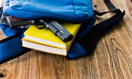 student threats, when students bring guns to schools: gun falling out of backpack on top of yellow book