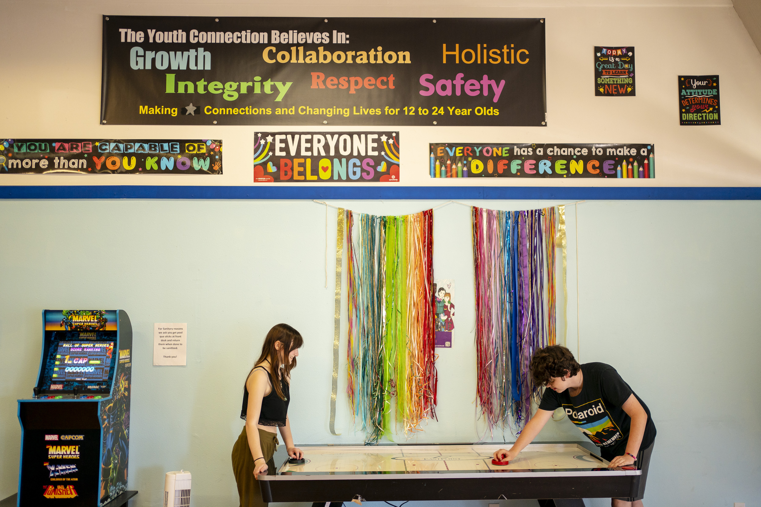 Youth homelessness: Two people wearing black shirts play air hockey