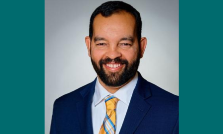 Dennis Quirin newsmaker headshot; smiling, bearded man in suit and tie