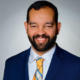 Dennis Quirin newsmaker headshot; smiling, bearded man in suit and tie