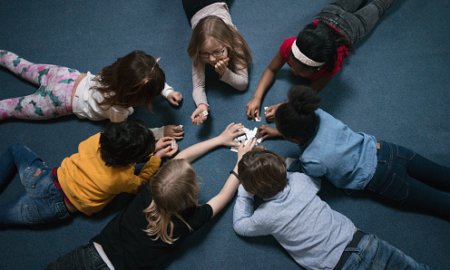 Underserved student education program evaluation grants; students laying in circle on floor learning