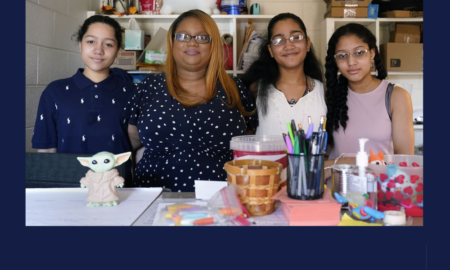 summer school: 3 young women and one lder woman stand together behind table of colorful craft supplis in front of more supplies on wall shelving and a "Welcome" sign