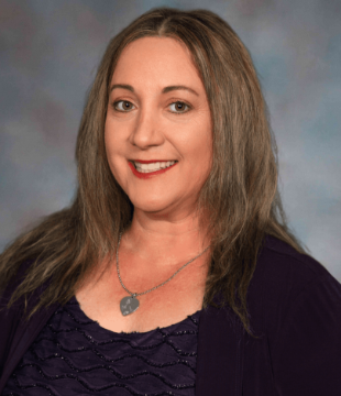 School Triage Trraining: Headshot of woman with long brown hair in black top smiling into camera